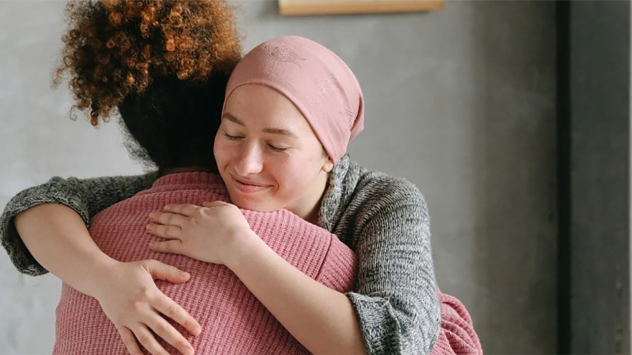 A cancer patient and a nurse embrace.