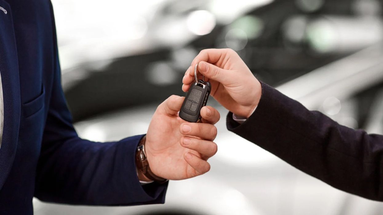 A car dealer and a customer exchanging a set of keys.