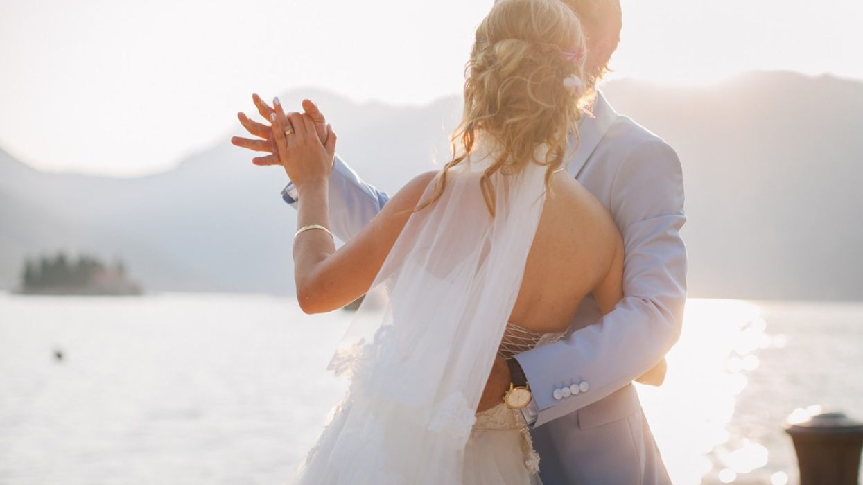A man and a woman in wedding attire share a dance together.