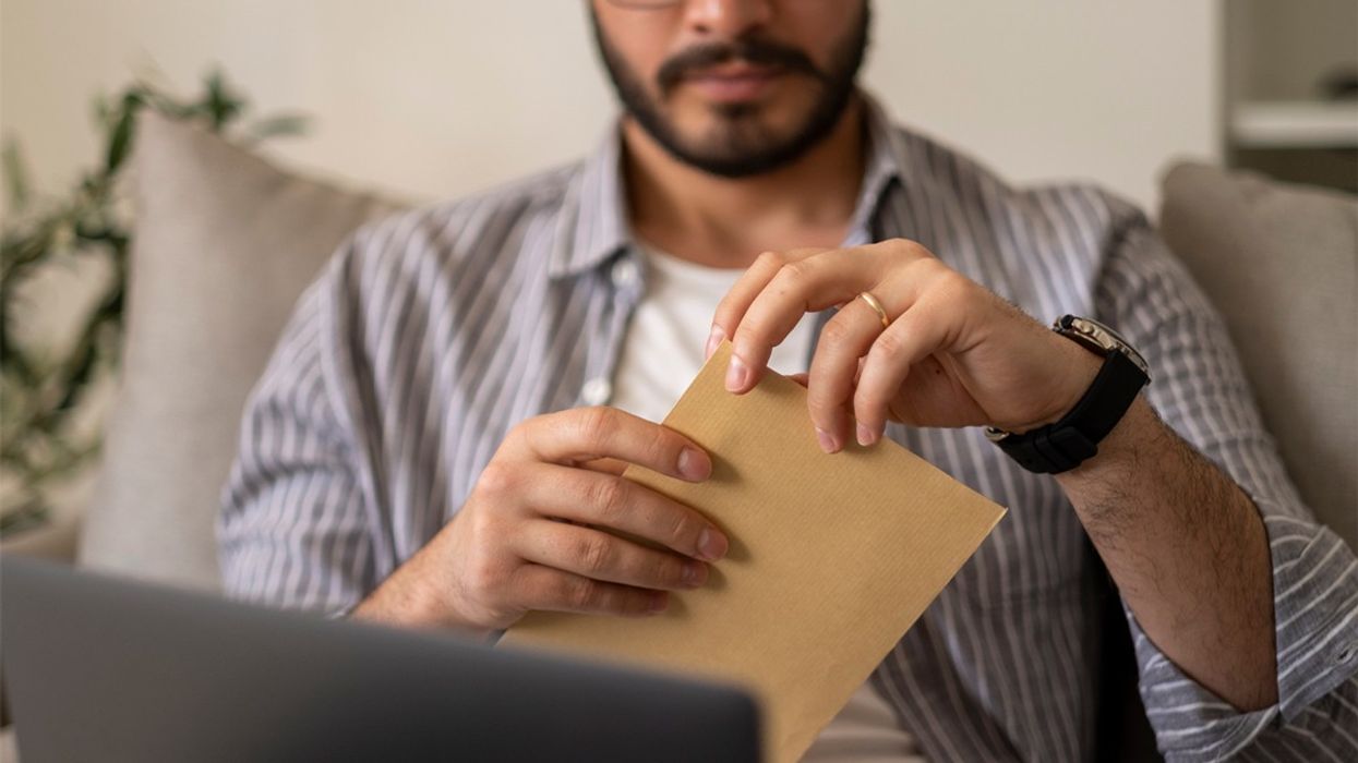 A man opens a bit of mail with an anxious expression.