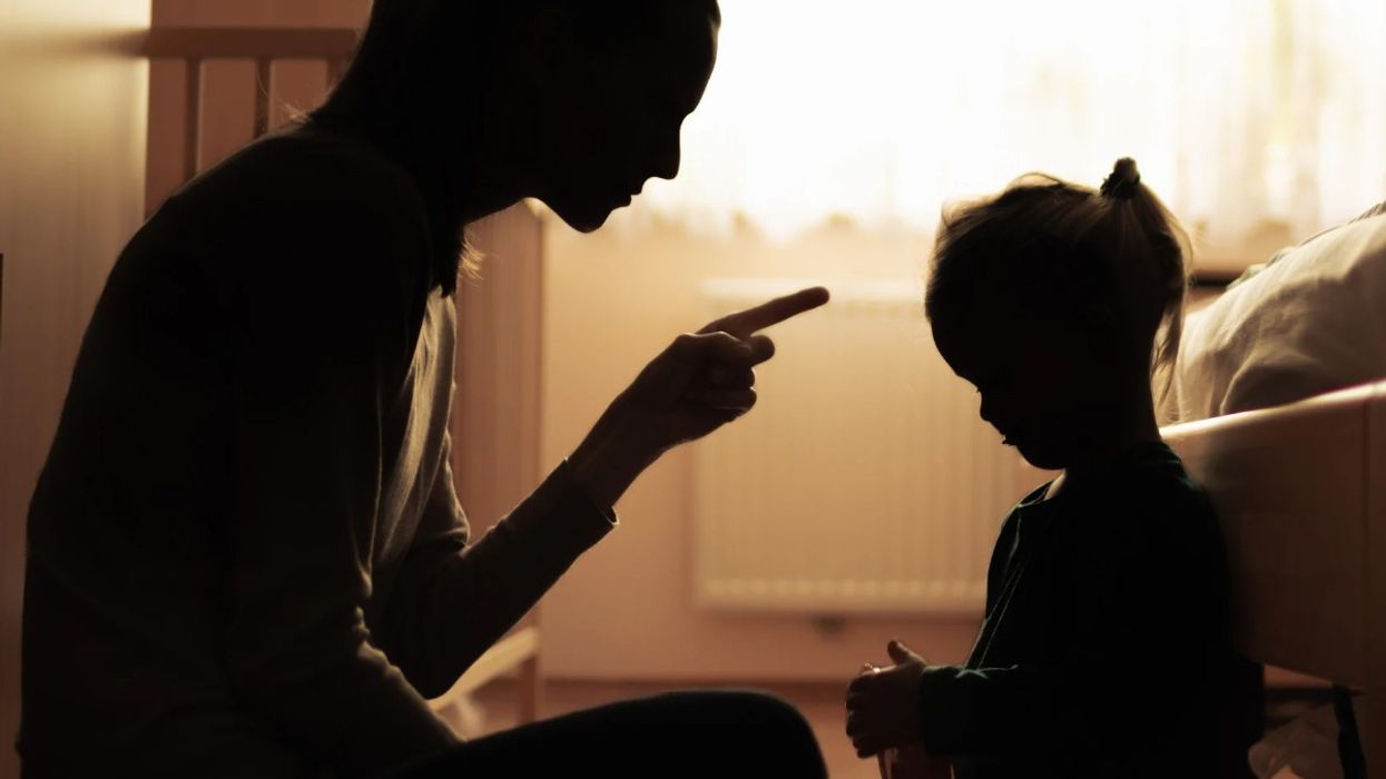 A mother scolds her child in a dim room.