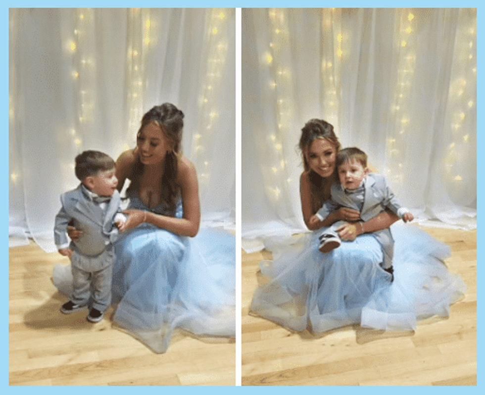 A young mother in a prom dress holding her toddler son in a tiny suit, both smiling at the camera.