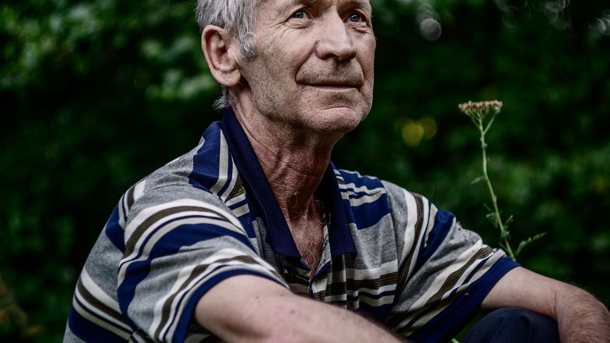 an older man sits down staring into the distance