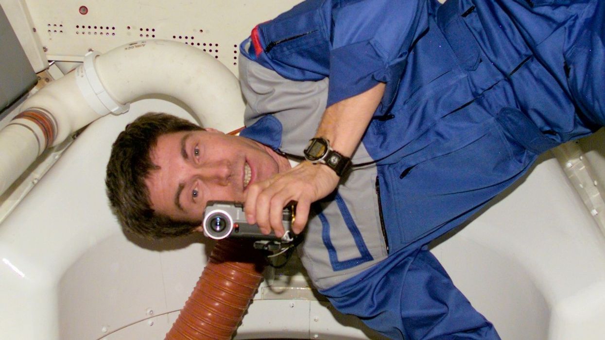 Cosmonaut Sergei Krikalev floating aboard the space station, holding a camcorder in microgravity, surrounded by equipment.