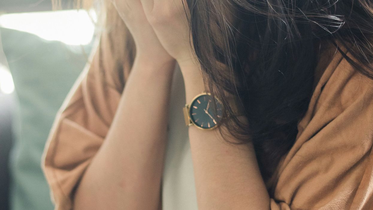 woman in brown shirt covering her face